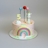 Children's birthday cake with rainbow, unicorn, and number 5 decorations on a white background